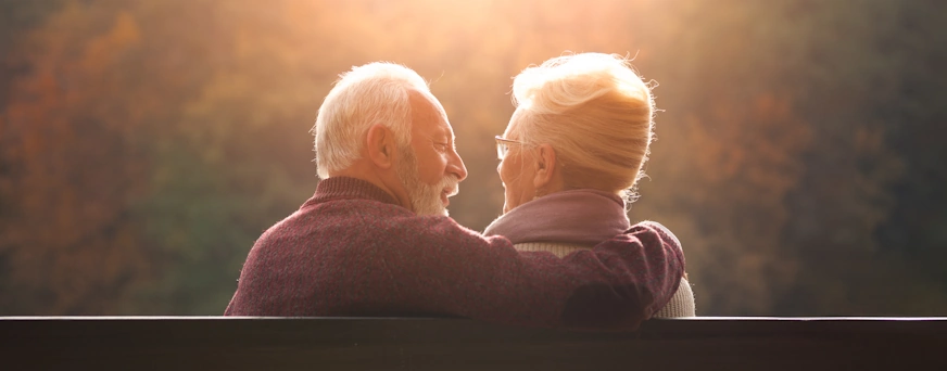 Life Assure Senior Couple Sitting On Bench In Autumn Park Hero